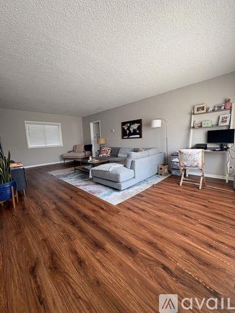 A living room with a grey couch and a wooden floor.