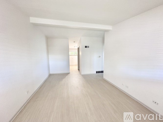 A spacious room with wooden flooring and white walls.