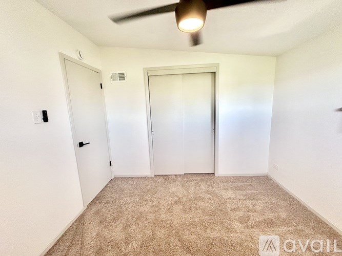 A room with a carpeted floor and a ceiling fan.