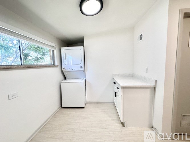 A white kitchen with a window and a fridge.