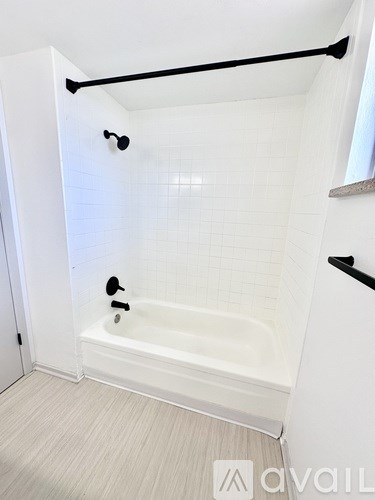 A white bathroom with a tub and a towel bar.