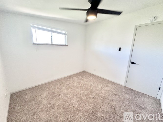 A room with a carpeted floor, a ceiling fan, and a window with blinds.