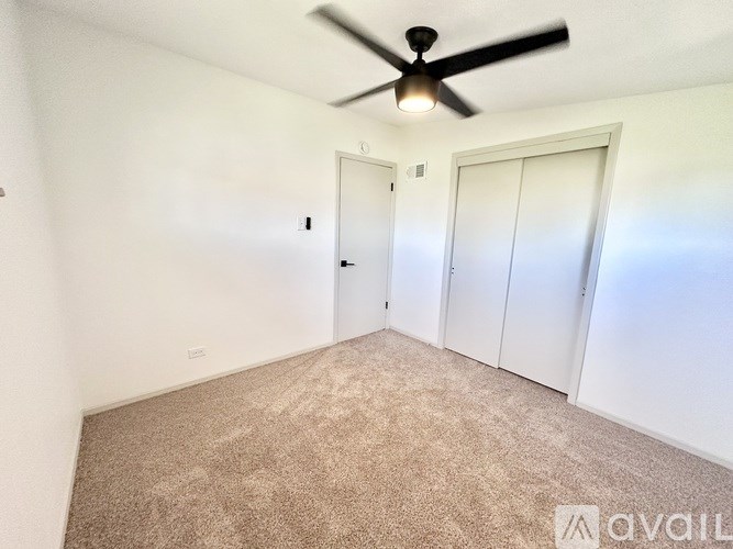 A room with a ceiling fan and carpeted floor.