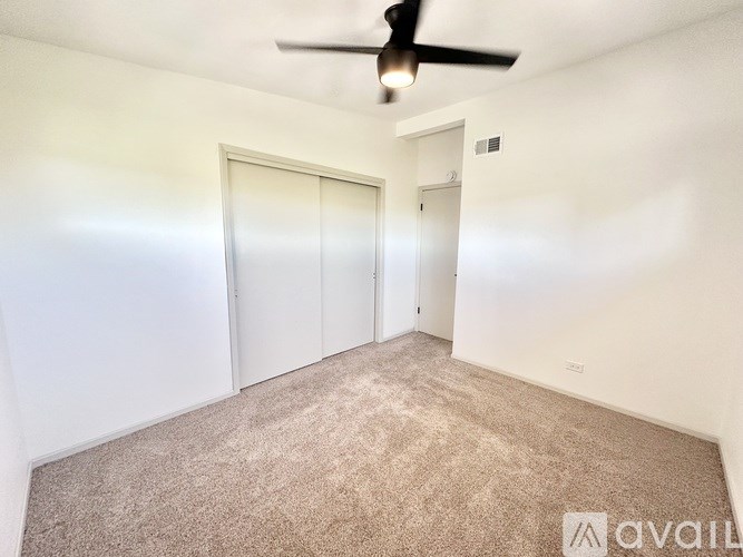 A room with a ceiling fan and carpeted floor.