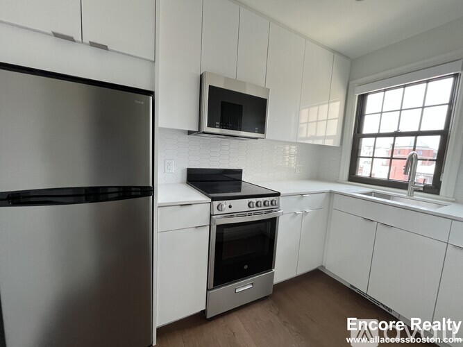 A kitchen with white cabinets and a stainless steel refrigerator.