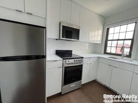 A kitchen with white cabinets and a stainless steel refrigerator.