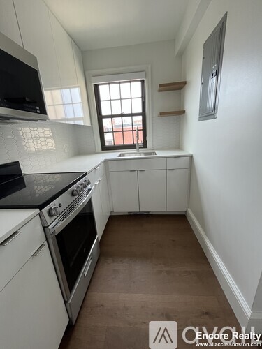 A kitchen with white cabinets and a black countertop.