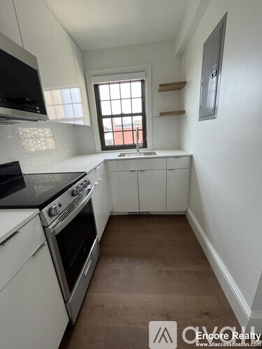 A kitchen with white cabinets and a black countertop.