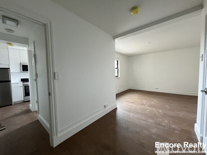 A room with white walls and wooden flooring is shown.