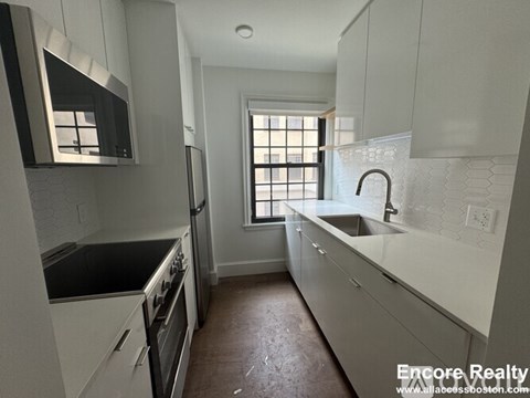A kitchen with white cabinets and black countertops.