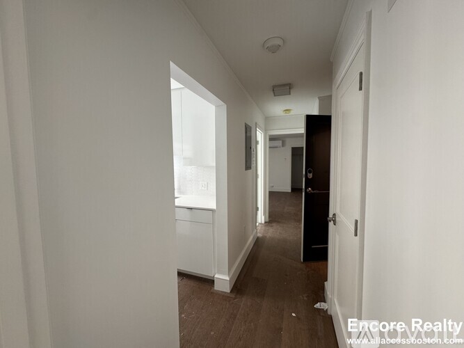 A long hallway with a door on the right and a window on the left.