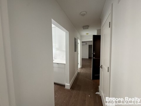 A long hallway with a door on the right and a window on the left.