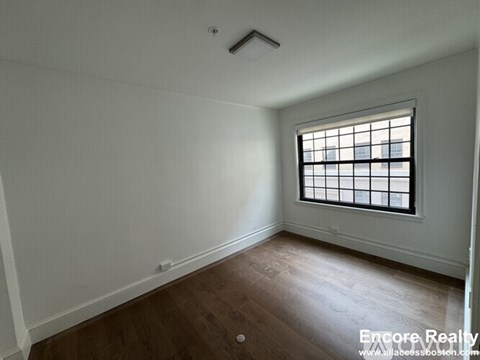 A room with a window and wooden flooring.