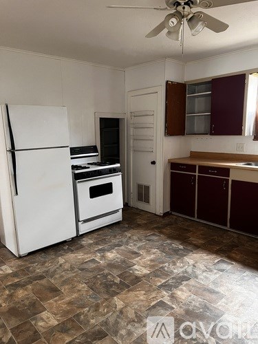 A kitchen with a white refrigerator and a fan on the ceiling.