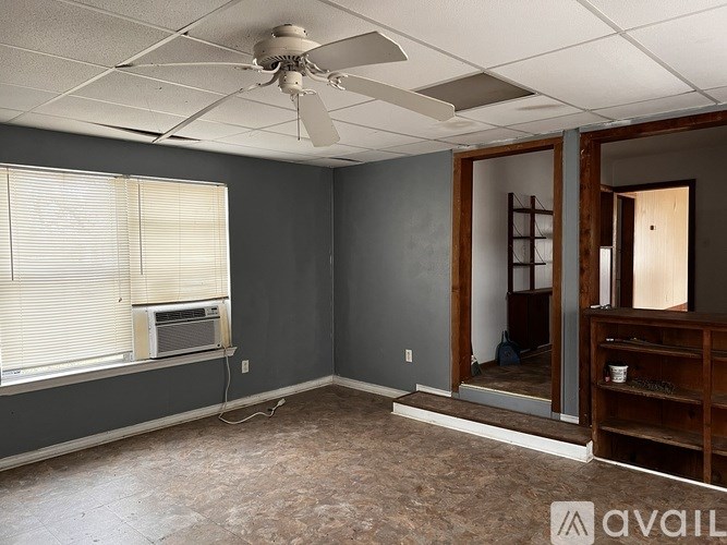 A room with a ceiling fan and a window with blinds.