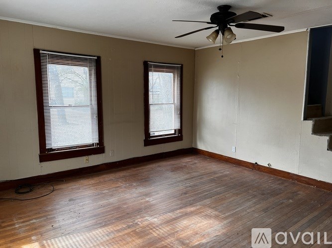 A room with wooden floors and two windows.