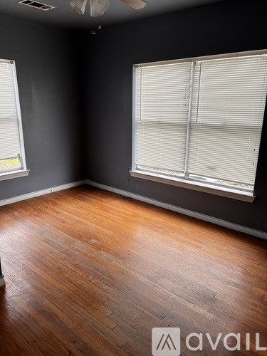 A room with wooden floors and a window with blinds.