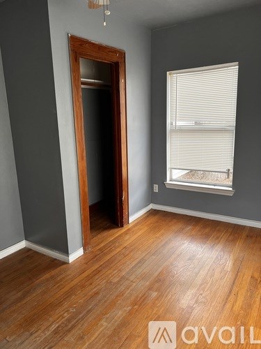A room with wooden floors and a window with blinds.