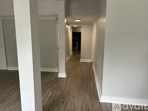 A long hallway with wood flooring and white walls.
