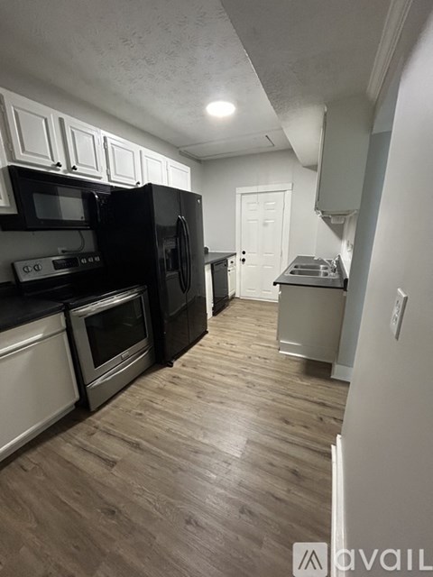 A kitchen with black appliances and wooden floors.