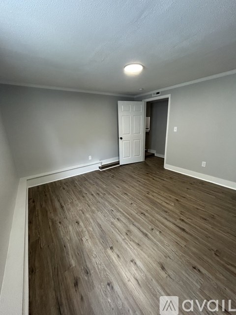 A room with wooden flooring and a white door.