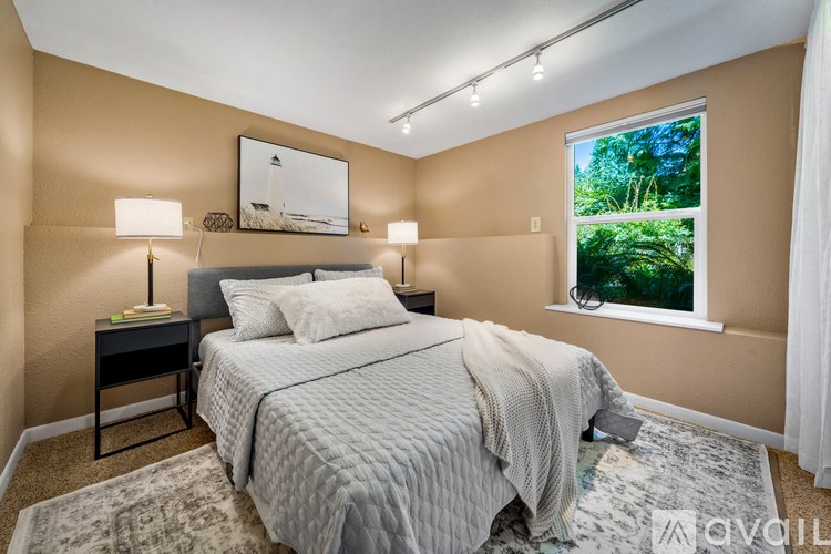 A bedroom with a bed, two lamps, and a picture on the wall.