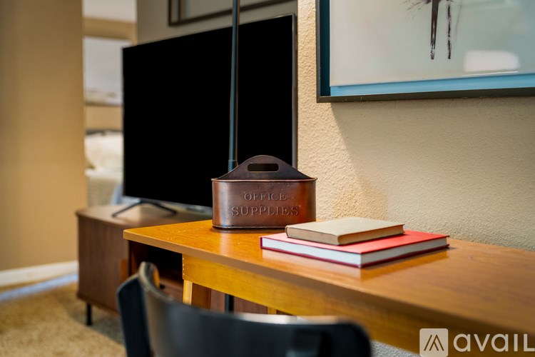 A brown leather box labeled "Office Supplies" sits on a wooden desk next to a book.