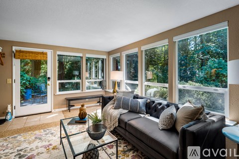 A living room with a black couch and a glass coffee table.