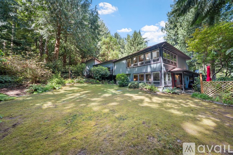 A house with a large yard is surrounded by trees.