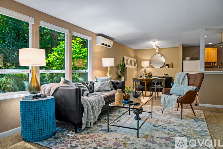 A well-lit living room with a grey sofa, a blue side table, and a floral rug.