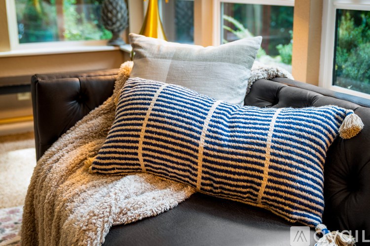 A blue and white striped pillow on a black leather chair.