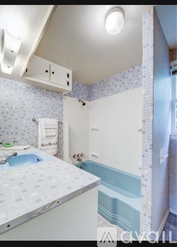 A small bathroom with a blue and white tiled shower.