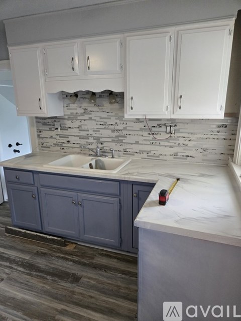 A kitchen with a white counter top and a sink under a cabinet.
