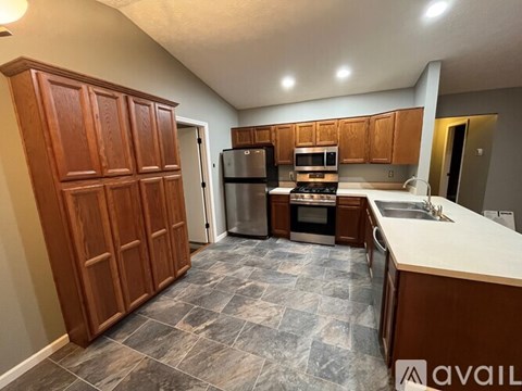 A kitchen with wooden cabinets and a stone floor.