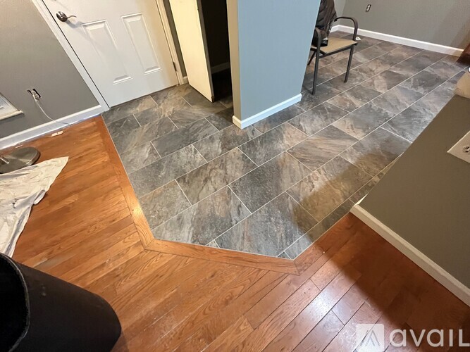 A kitchen with a tile floor and wooden flooring.