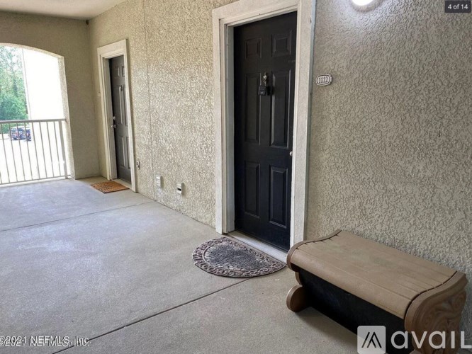 A room with a black door, a window, and a bench.