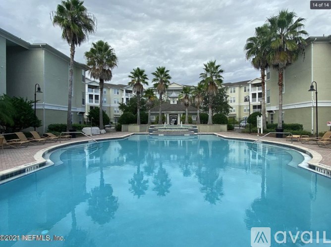 A swimming pool surrounded by palm trees and apartment buildings.
