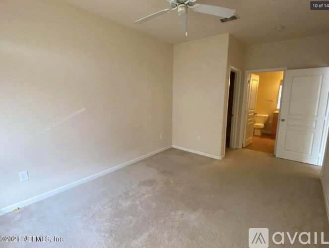 A room with a ceiling fan and carpeted floor.