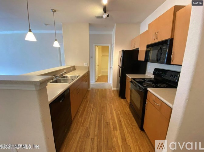 A kitchen with wooden floors and black appliances.