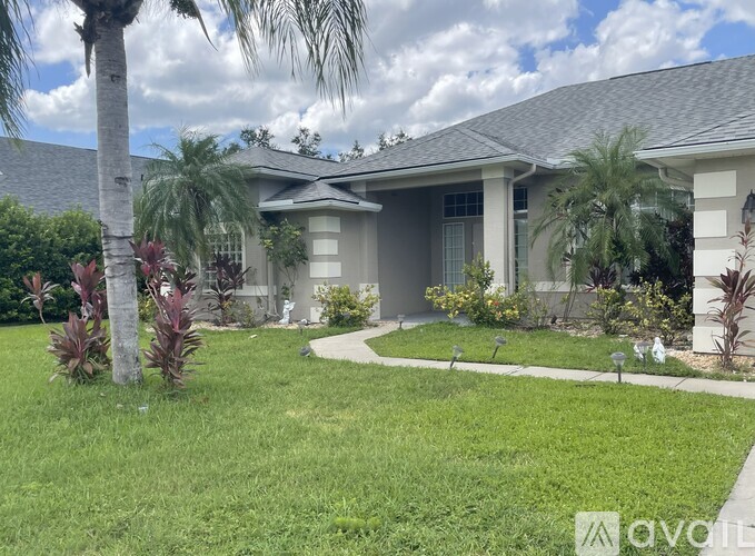 A house with a lawn and palm trees in front.