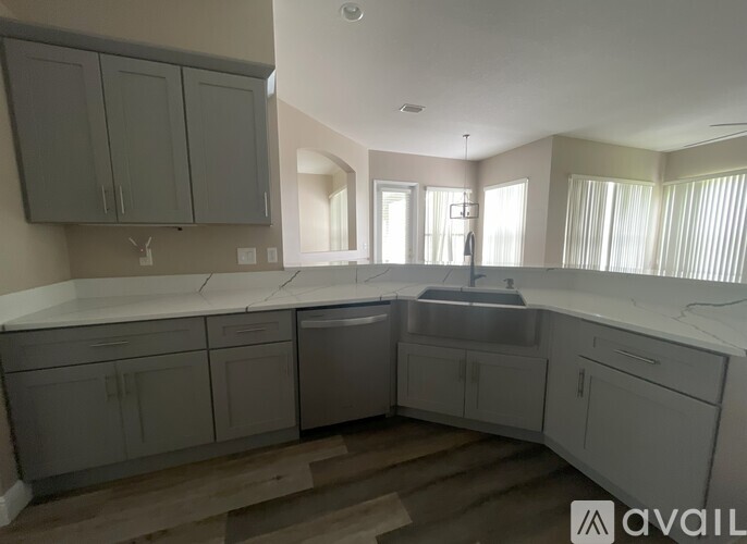 A kitchen with grey cabinets and a white countertop.