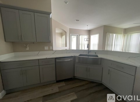 A kitchen with grey cabinets and a white countertop.