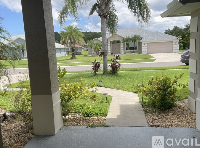 A residential area with a house, palm trees, and a well-maintained lawn.