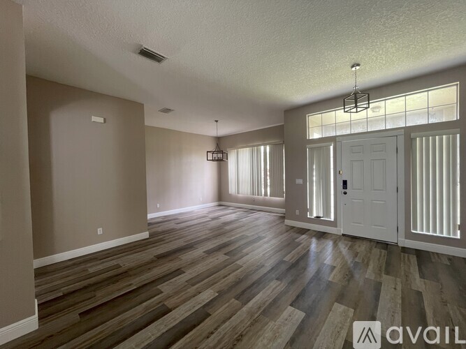 A spacious room with wooden flooring and a white door.
