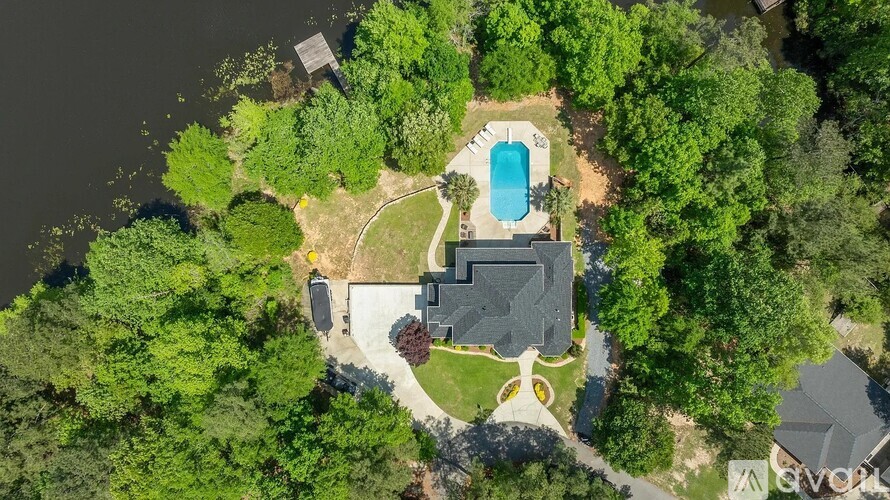 A bird's eye view of a house with a swimming pool surrounded by trees.