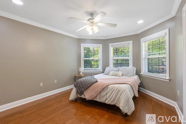 A bedroom with a bed, a ceiling fan, and two windows.