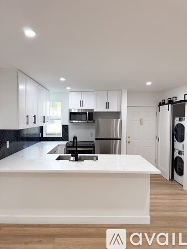 A modern kitchen with a white island and stainless steel appliances.