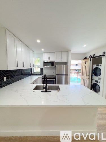 A kitchen with white cabinets and a marble countertop.