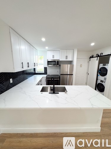 A kitchen with white cabinets and a marble countertop.