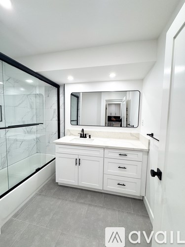 A bathroom with a white cabinet and a large mirror.